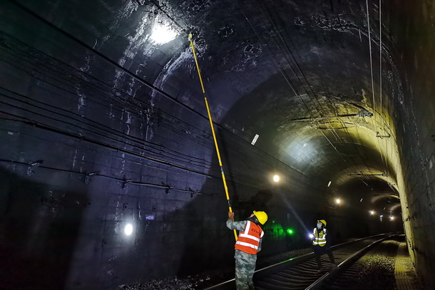 图为两名供电维修工相互配合隧道打冰